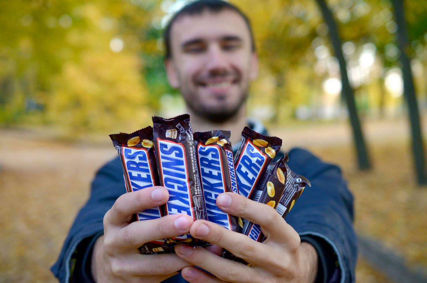 Man holding a large amount of Snickers bars